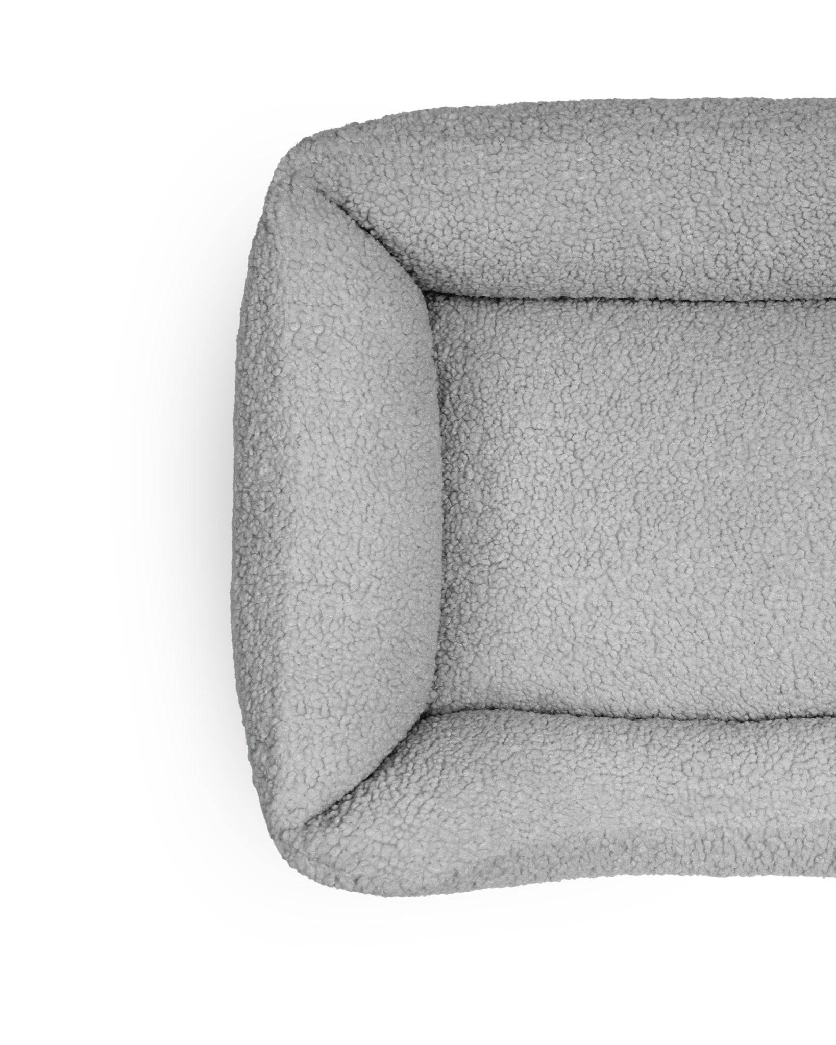 Soft, cozy teddy lounge pet bed from The Dogs Company with plush stone-colored fabric for comfortable relaxation.