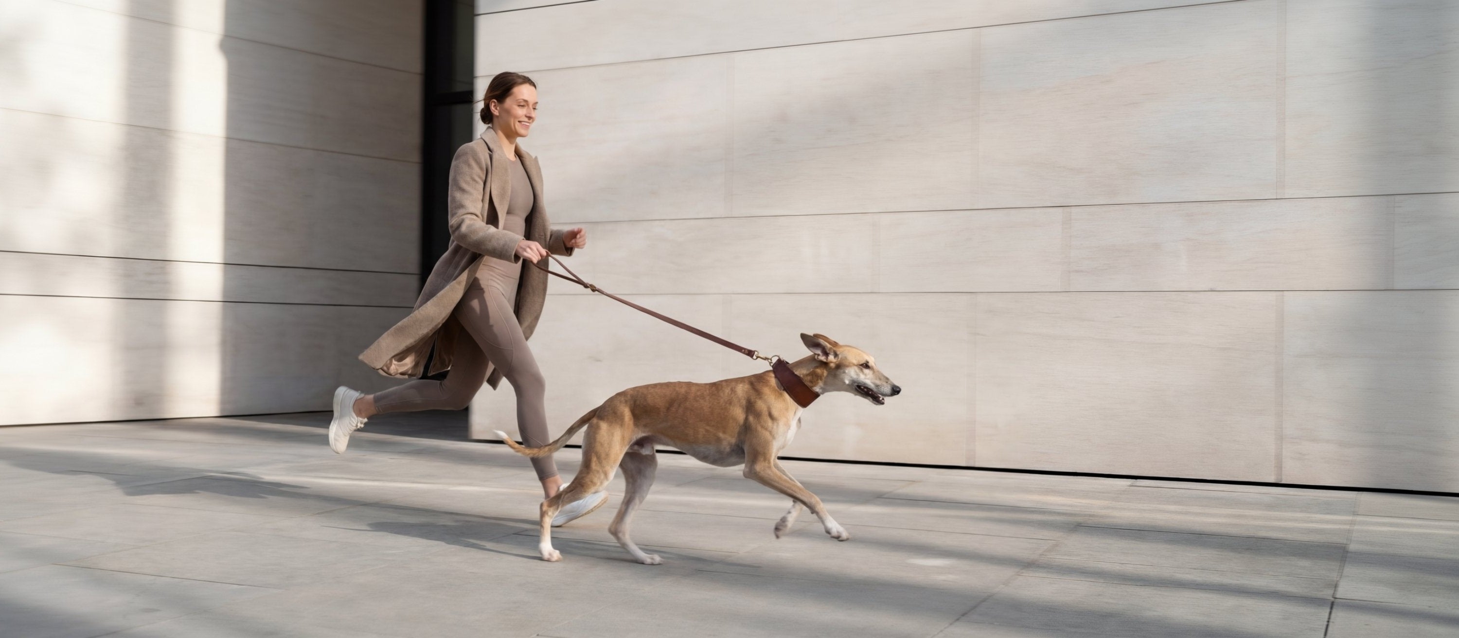 Woman walking a dog on a leash in an urban setting
