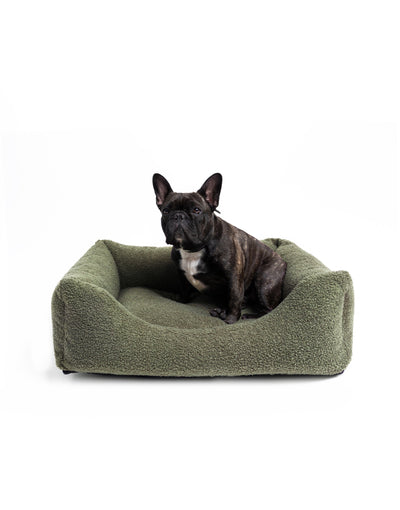 Cream-colored bouclé pet lounge bed by The Dogs Company with plush, rounded design for comfortable lounging.